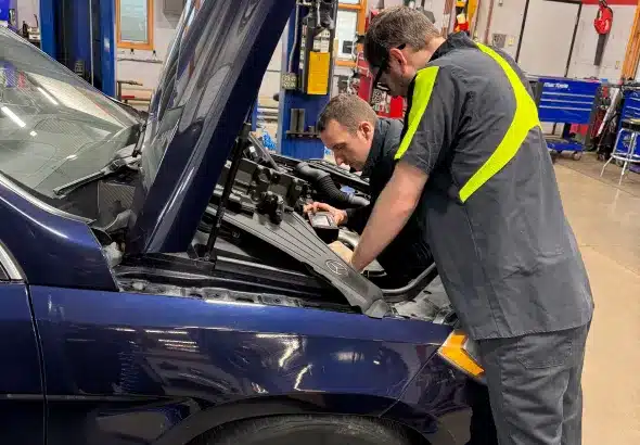 Vehicle Diagnostics in Sheyboygan WI, by NexGen Automotive. Image of two auto technicians working under the hood of a car, performing diagnostics and repairs in an auto repair shop.