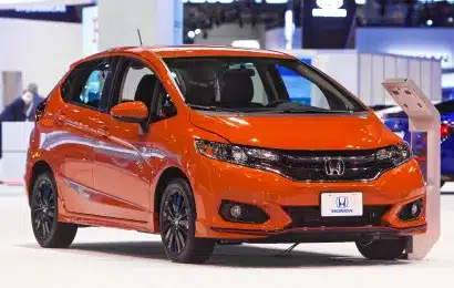 An orange Honda hatchback displayed in a well-lit showroom, highlighting its compact design and modern features.