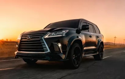 A black SUV driving on a rural road at sunset, highlighting its luxury and powerful performance.