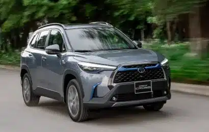 A gray SUV driving on a tree-lined road, showcasing its robust design and smooth performance.