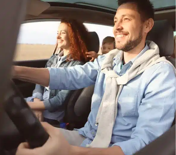 Happy family driving in a car with a functional air conditioning system, showcasing the comfort and importance of a well-maintained auto A/C.