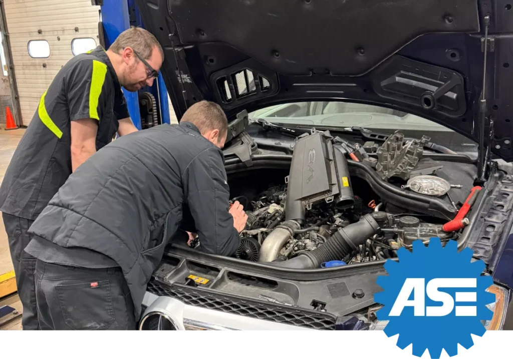 Two ASE-certified technicians working under the hood of a vehicle in an auto repair shop, showcasing their certification and expertise.