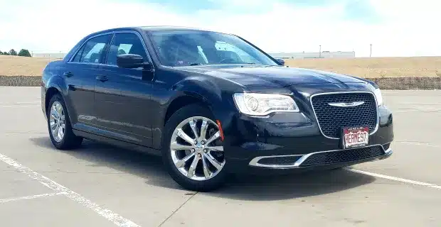 A black Chrysler sedan parked in an open parking lot, showcasing its elegant design and smooth lines.