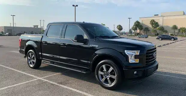 A black Ford F-150 truck parked in a spacious parking lot, showcasing its robust design and modern features