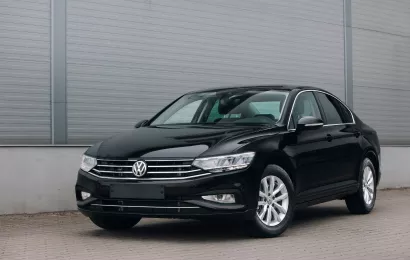 A black Volkswagen sedan parked outdoors against a modern building backdrop, showcasing its sleek design.