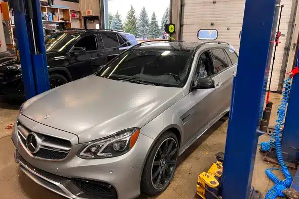 A silver Mercedes-Benz parked inside an auto repair shop, ready for maintenance or repair.