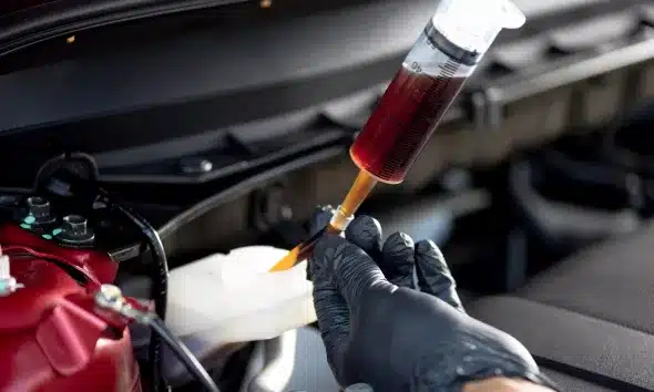 Checking the brake fluid level in a car's reservoir during a pre-trip inspection.