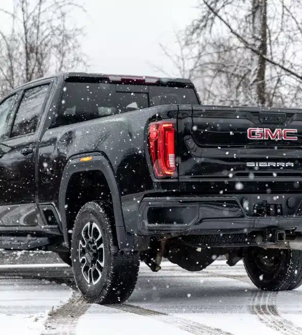 A black GMC Sierra truck navigating through a snowy landscape, emphasizing the importance of using the right tires for safe winter driving.