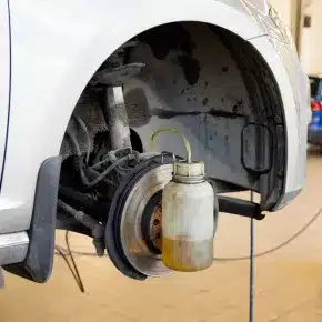 A car's wheel hub and brake system exposed during a brake fluid change. The image emphasizes the importance of maintaining brake fluid levels for optimal braking performance and safety.