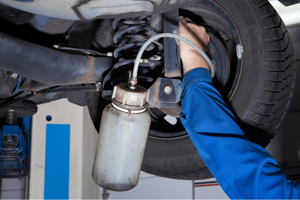brake fluid flashing, auto repair in Sheboygan, WI at NexGen Automotive. Image of a mechanic performing a brake fluid flush under a vehicle, ensuring optimal braking performance and long-lasting safety on the road.