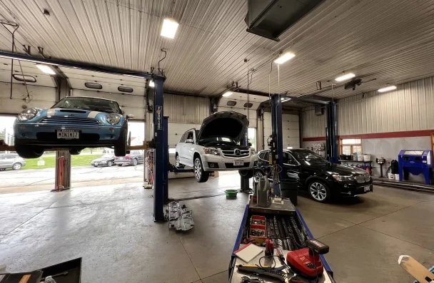 European auto repair services in Sheboygan, WI with NexGen Automotive. The image depicts three cars being lifted: a blue Mini Cooper for wheel alignment, a Mercedes undergoing oil change service, and a black BMW for preventative maintenance. Trust us for expert European auto repair near you.