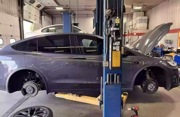 Need brake service in Sheboygan, WI with NexGen Automotive brake repair near me. The image shows a bluish-grey car being lifted for brake service and repair maintenance. Trust us for expert brake repair near you.